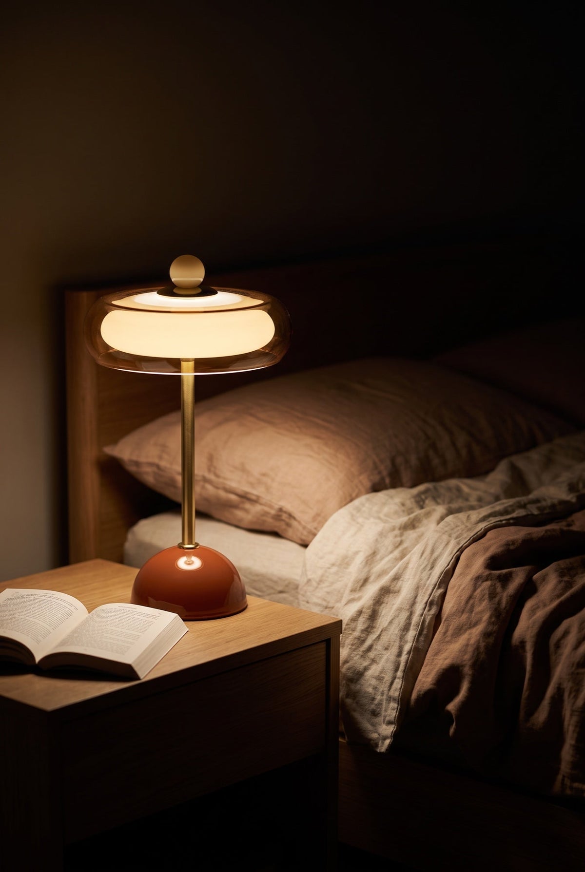 Lampe à poser allumée sur une table de chevet, le soir