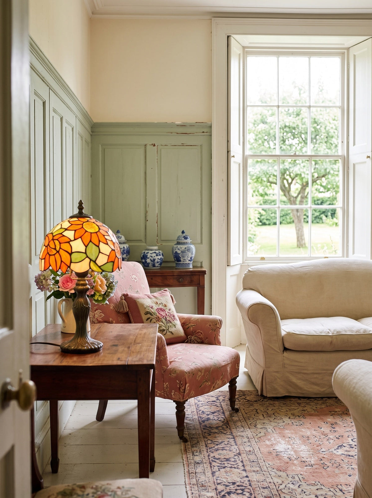 Lampe en vitrail sur un guéridon, fauteuil fleuri et porcelaine bleu et blanc